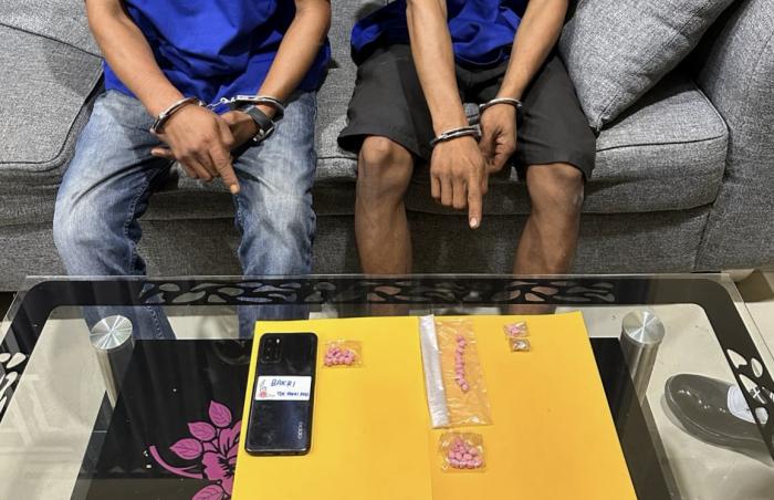 Dua tersangka kasus narkotika memperlihatkan barang bukti pil ekstasi saat diamankan Satres Narkoba Polres Dumai. Polisi menyita 35 butir pil ekstasi yang disembunyikan di bawah pintu rumah dan paha pelaku dari dua lokasi berbeda di Kota Dumai.